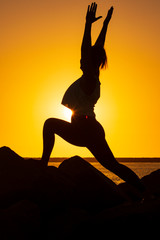Silhouette of a young woman doing Yoga pose at sunset