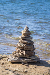 Fototapeta na wymiar Balanced Rock Stack found on Shore of Lake with lapping waves behind 