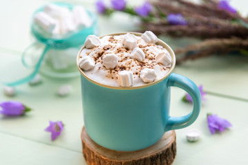 Hot coffee drink with marshmallows and foam in a light blue Cup.