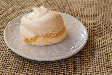 close up of homemade sigh or meringue is a sweet made from egg white, sugar and lemon on white plate and jute towel.