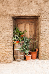 Traditional wine barrel with flowers in front of an old wooden door of a house.