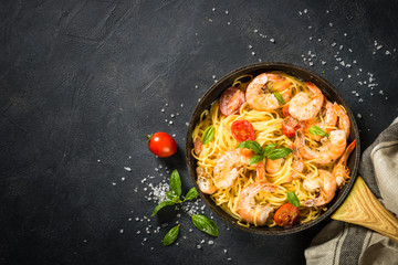 Pasta seafood with shrimp on black table.