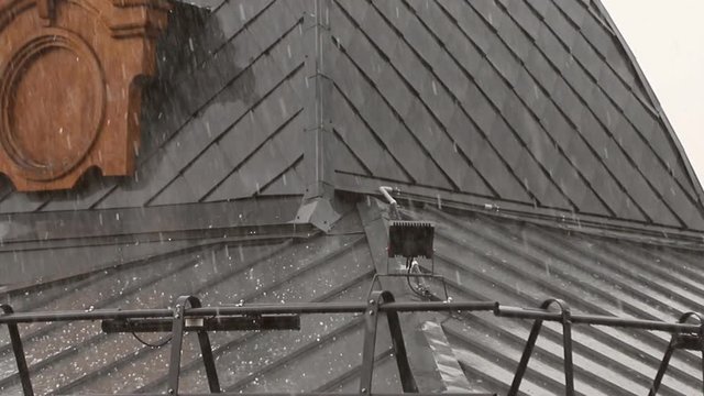 hail falls on the roof of a house during a thunderstorm. Roof damage from hail. The hail hit the roof of the house. Roof damage from a thunderstorm
