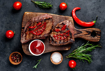 Two grilled beef monster steaks with spices for halloween on stone background