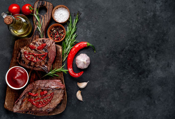  Two grilled beef monster steaks with spices for halloween on stone background with copy space for...