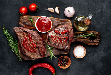 Two grilled beef monster steaks with spices for halloween on stone background