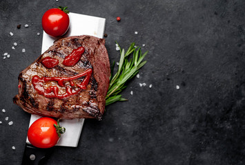 Grilled beef steak with spices on a butcher's knife for Halloween on stone background with copy...