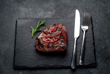 grilled beef steak with spices, knife and fork for halloween on stone background