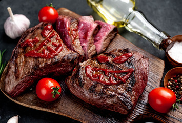 Two grilled beef monster steaks with spices for halloween on stone background