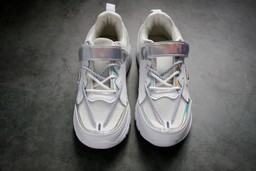 Women's white fashion sneakers on a cement background close-up, top view. copy space