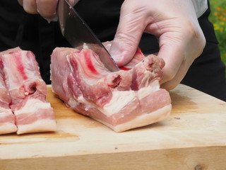 a chef in gloves and a black apron cuts a pork loin into steaks. the cooking of the steaks. meat. pork.