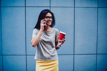 Cheerful female office manager talking on mobile during coffee break enjoying free time, happy businesswoman discussing details of new project with colleague on phone standing