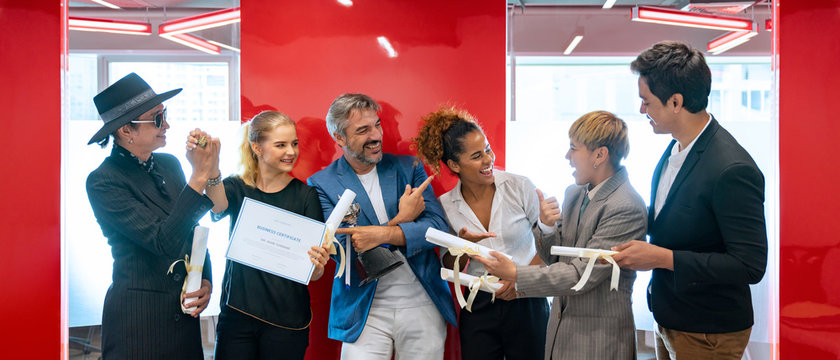 Group Of Cheerful Multiethnic Business People Holding Trophy And Certificates Of Achievement. Successful Diverse Team Of LGBT Celebrating At The Workplace. 