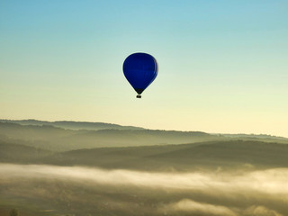 Early morning mist as viewed from a hot air balloon at sunrise, with another balloon visible on the distant horizon