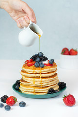 stack of pancakes with syrup and berries