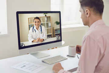 Online doctor. A young businessman is sitting in his office and uses the services of an online...