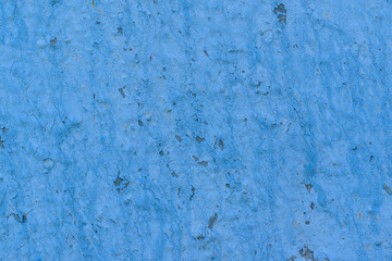 Wall surface with old backdrop paint. The color of the paint is blue. Unevenness, cracks, flaking, traces of rust.
