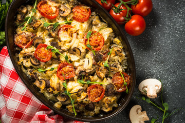 Baked meat with vegetables top view on black table.