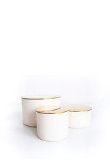 three beige cylinder podiums with golden tops of different heights on a white background. Luxurious showcase for advertising and product promotion..