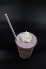 Bebida de taro frappé con crema batida y popote en fondo negro