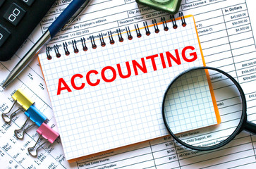 Text Accounting on notepad with calculator, clips, pen on financial report