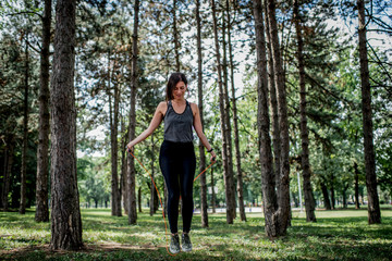 Young woman exercising with jumping rope at public park