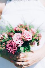 The bride holds a wedding bouquet from roses in her hands, wedding day flowers. Beautiful bohemian wedding flower bouquet. Girl in a dress with a bouqet of rose.
