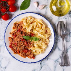 Traditional italian pasta bolognese on a white plate on a marble background