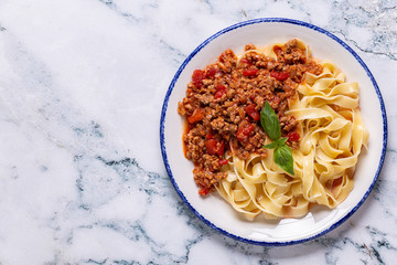 Traditional italian pasta bolognese on a white plate on a marble background
