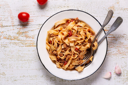 Traditional italian pasta bolognese on a white plate on a wooden background