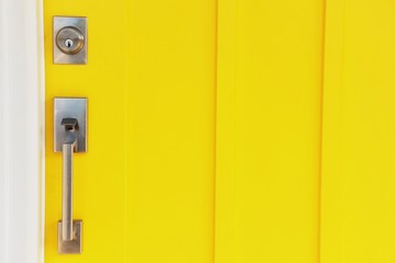 yellow door with a modern metal handle and lock