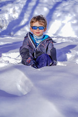 Fototapeta na wymiar Soft focus background. Young Boy With Sunglasses Playing In The Snow. Winter sunny day on the french alps