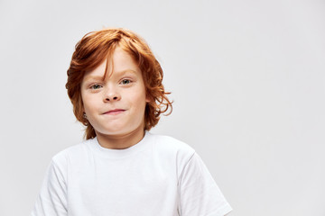 Cute redhead boy in white t-shirt studio smile 