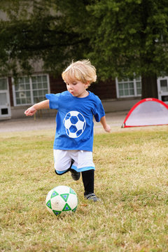 Caucasian boy playing soccer in field