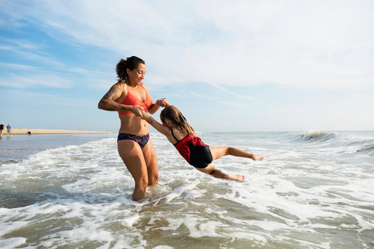 Mother and daughter playing in waves on beach