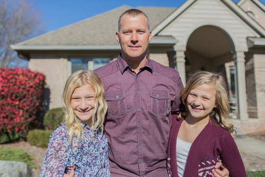 Caucasian father and daughters smiling in yard