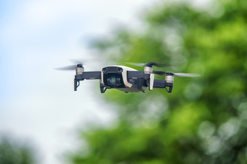 Small drone in flight against defocused foliage