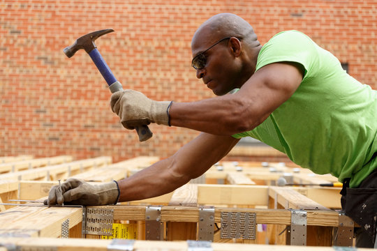 Side view of man hammering nail at construction site