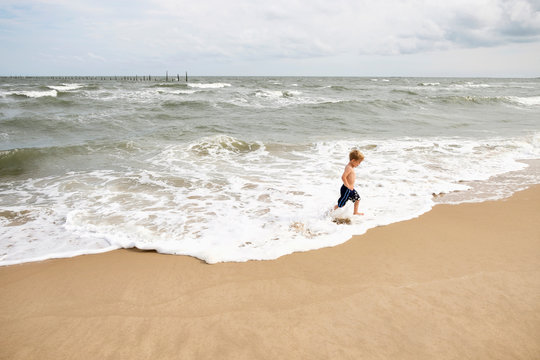 Caucasian boy running in waves at beach