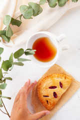 puff buns with raspberries on a vintage plate on a white background close-up. Breakfast with tea. Top view. a woman's hand reaches out to