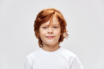 Cheerful redhead child white t-shirt smile Studio gray isolated 