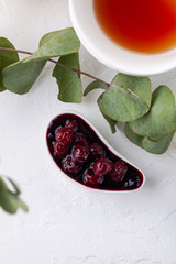 cherry jam in a white sauce pot and a mug of tea on a light background