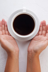 women's hands hold a white coffee mug on a white background.