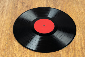 Old vinyl disc on wooden background. Old vintage vinyl record.