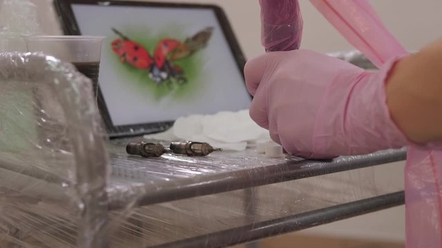Close-up of a tablet with a picture of a ladybug on a table in a tattoo parlor.