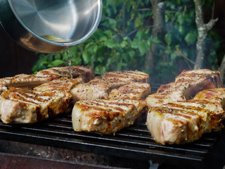 a man pours alcohol on the meat on the grill. roasting steaks on the fire. flambé.flamber.