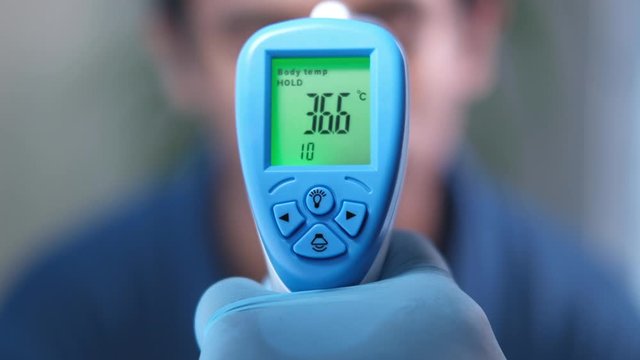 Hand holding inferred thermometer check temperature.