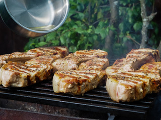 a man pours alcohol on the meat on the grill. roasting steaks on the fire. flambé.flamber.