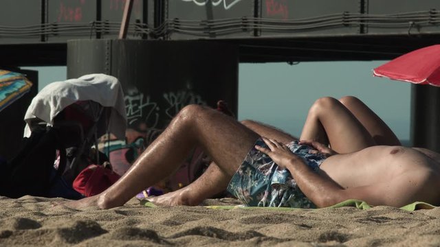 Torso of man sunbathing on the beach sand