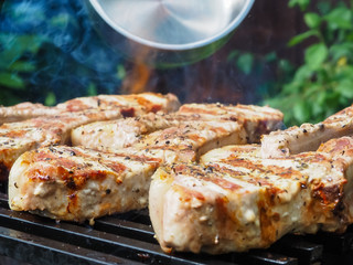 a man pours alcohol on the meat on the grill. roasting steaks on the fire. flambé.flamber.